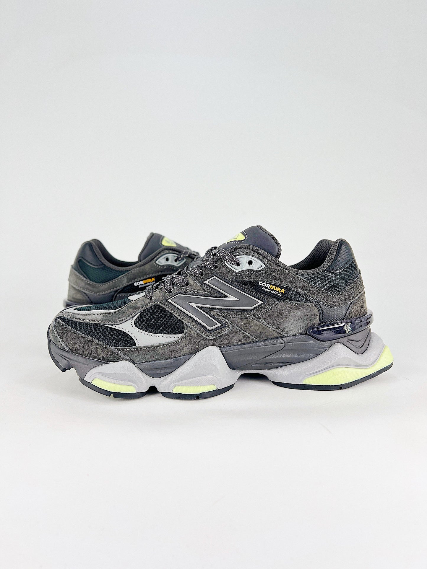 New Balance 9060 sneakers shown are in a black and cement colorway, often featuring a durable mesh and suede construction with Lime accents