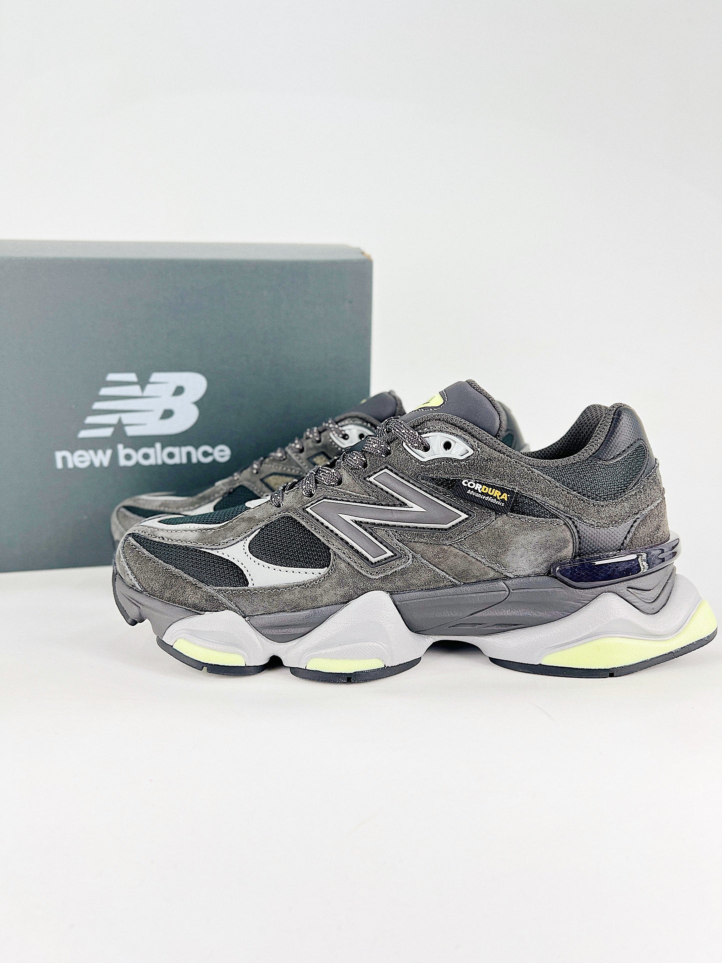 New Balance 9060 sneakers shown are in a black and cement colorway, often featuring a durable mesh and suede construction with Lime accents